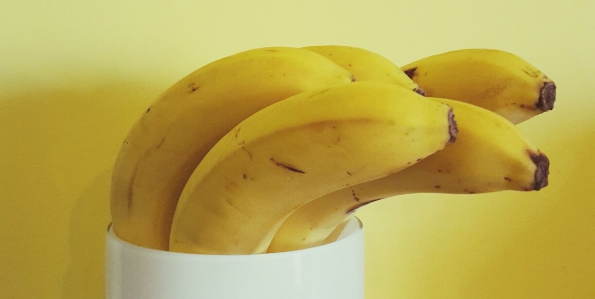 Close-Up Of Banana In White Container Against Yellow Wall