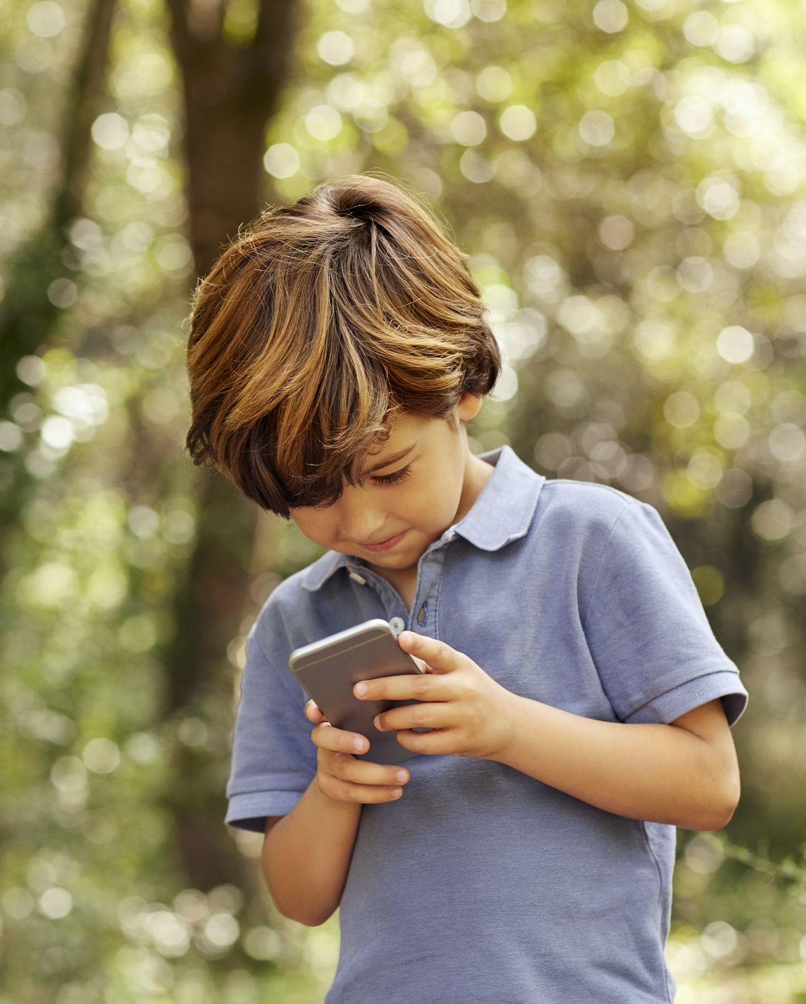 Smiling boy using mobile phone in forest