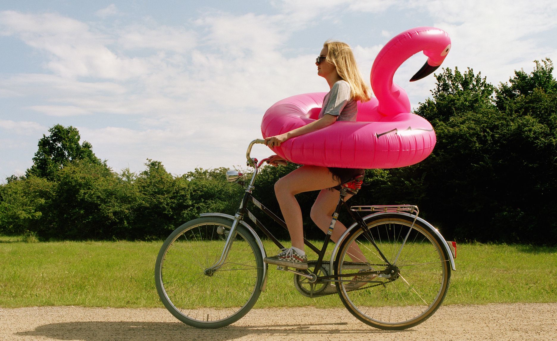 Young woman cycling with flamingo ring