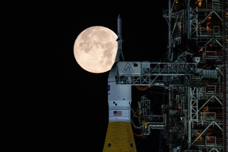 Una luna llena brilla sobre el SLS (Sistema de Lanzamiento Espacial) y la nave espacial Orión de la NASA, en lo alto de la plataforma de lanzamiento móvil, en las primeras horas del 1 de febrero de 2026. El cohete se encuentra actualmente en la plataforma de lanzamiento 39B del Centro Espacial Kennedy de la NASA en Florida, mientras los equipos se preparan para un ensayo general con simulación de lanzamiento para practicar los plazos y procedimientos para el lanzamiento de Artemis II. NASA/Sam Lott