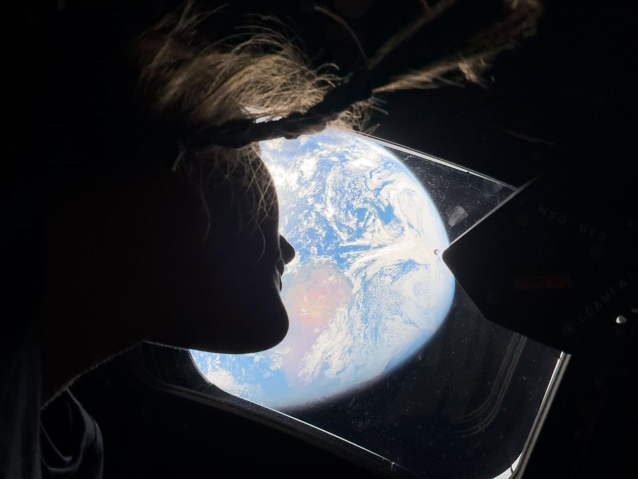 Christina Koch, astronauta de la NASA y especialista de la misión Artemis II, mira por una de las ventanas principales de la cabina de la nave espacial Orión, contemplando la Tierra, mientras la tripulación se dirige hacia la Luna.Crédito de la imagen: NASA